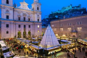 Salzburg’s Christkindlmarkt with Cathedral Road and Hohensalzburg Fortress illuminated in the background.