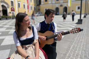 Dana and Dmitry perform a charming duet outside the Mondsee Basilica, where the iconic wedding scene in a beloved musical was filmed, enchanting visitors with their talent.