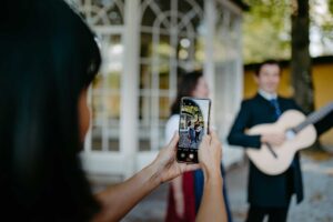 A visitor captures a joyous moment on their phone, framing entertainers performing in front of Hellbrunn's gazebo during the Private Sound of Maria Tour