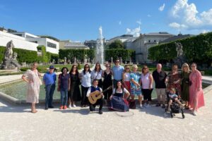 A group of people smiling in front of Mirabell Gardens in Salzburg