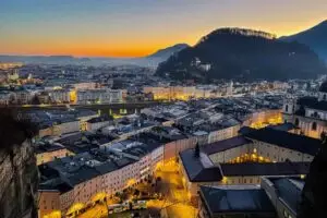 Sunset over Salzburg’s Old Town, with the city and surrounding mountains illuminated by a golden glow.